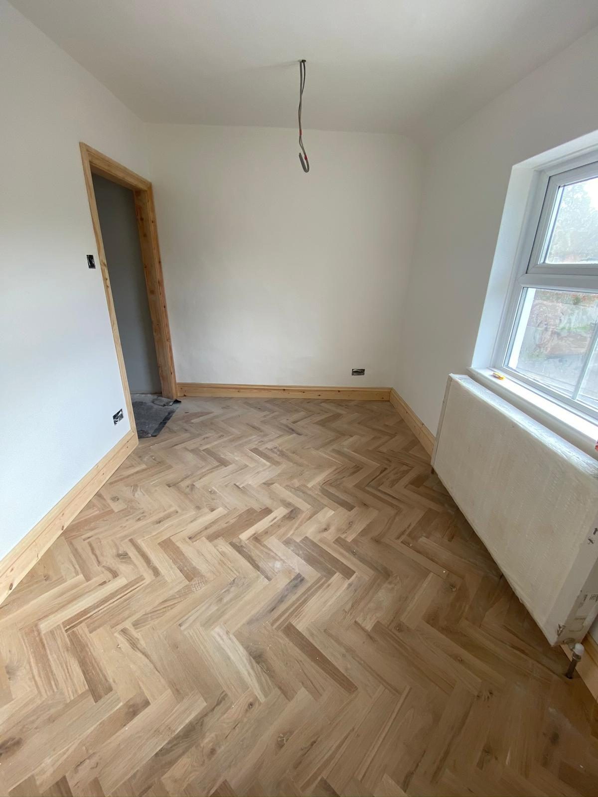 Newly laid herringbone parquet in a freshly painted bedroom
