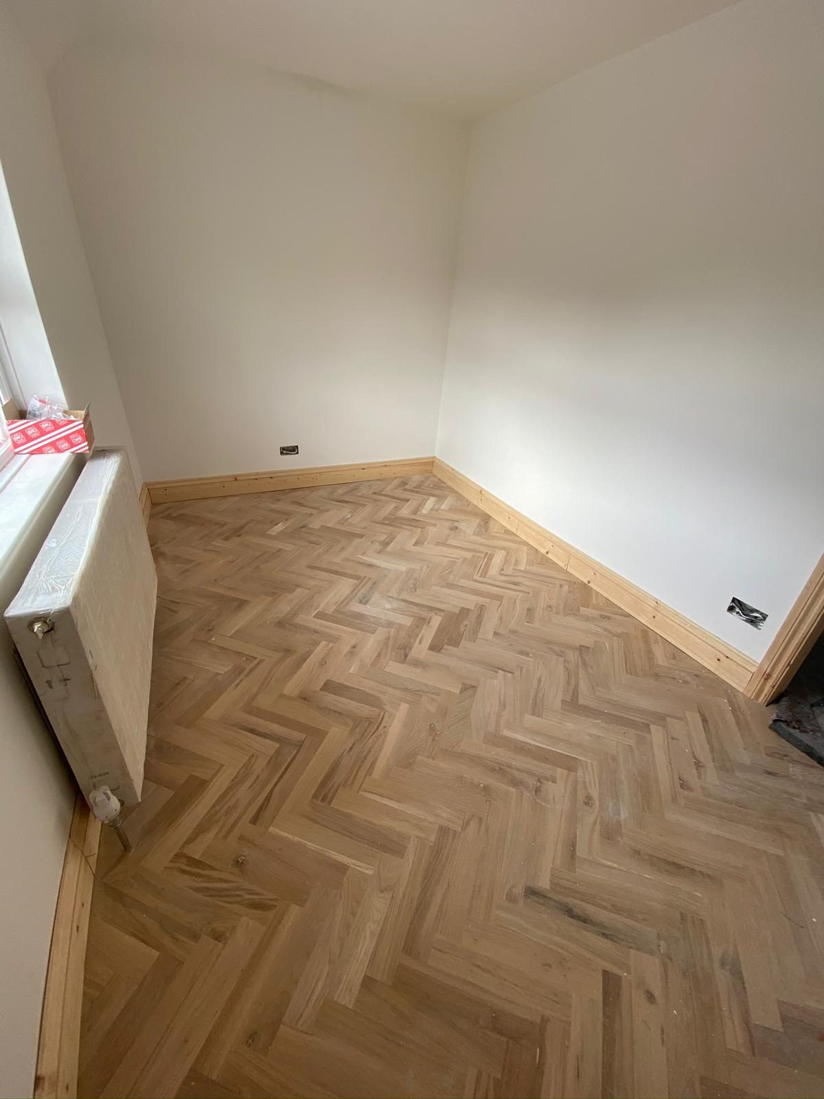 Herringbone parquet across a stripped-back room ready for second-fix