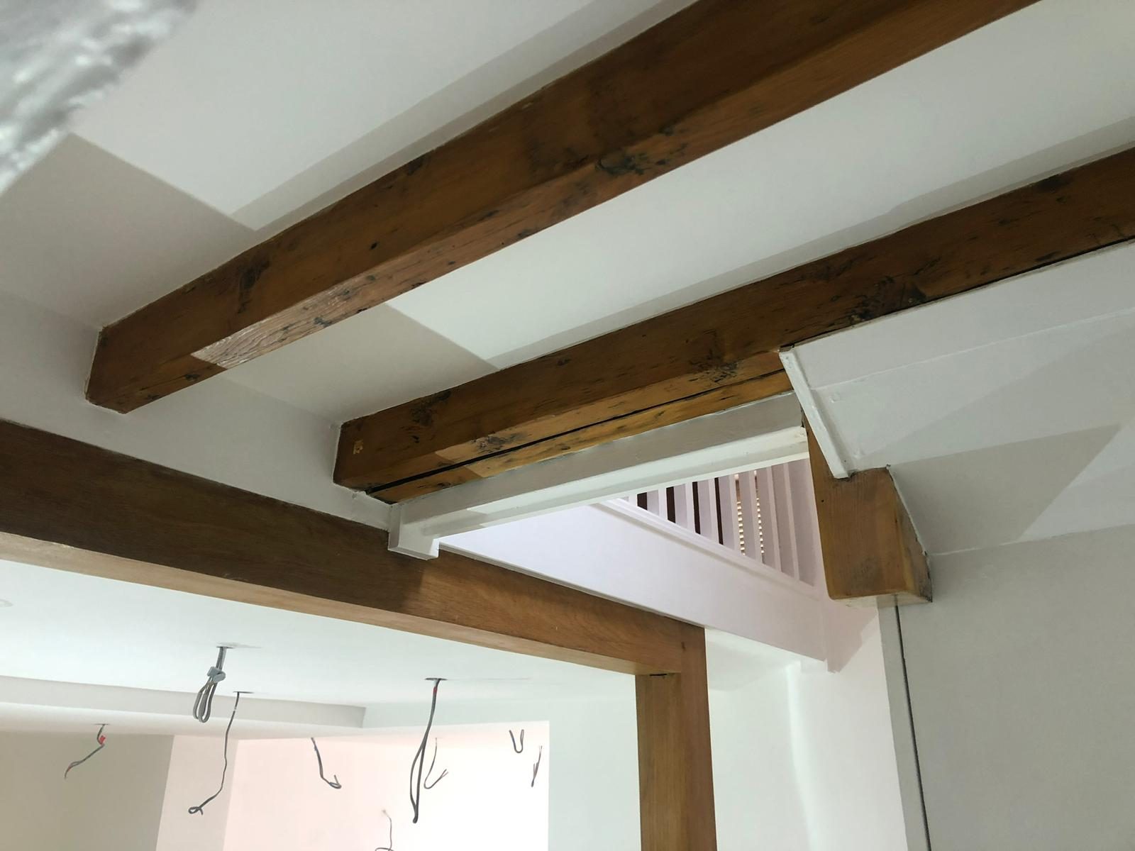 Cleaned-back original beams against fresh white plaster, mid-fit